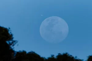 jet plane flying blue sky over huge moon