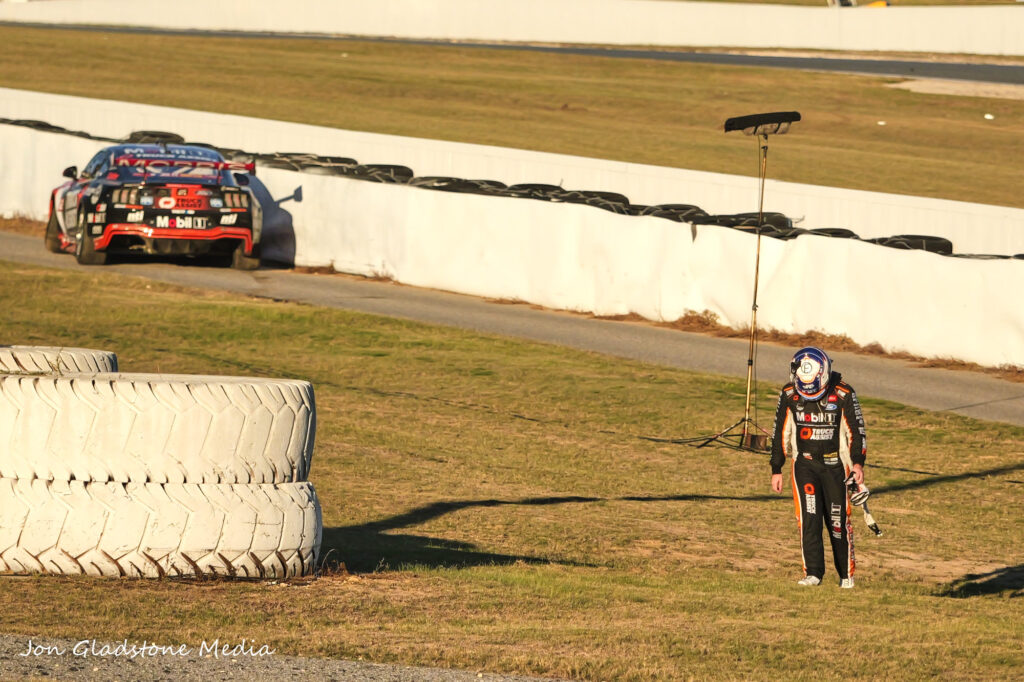 Driver walking away from his stopped racecar.